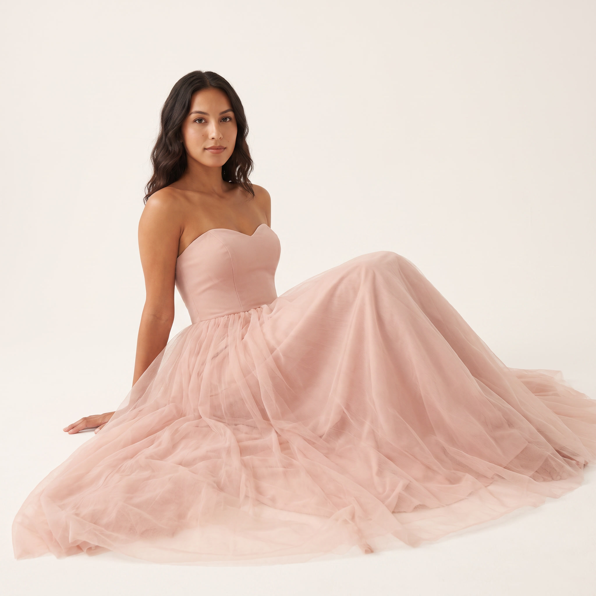 Model seated wearing blush pink tulle ball gown