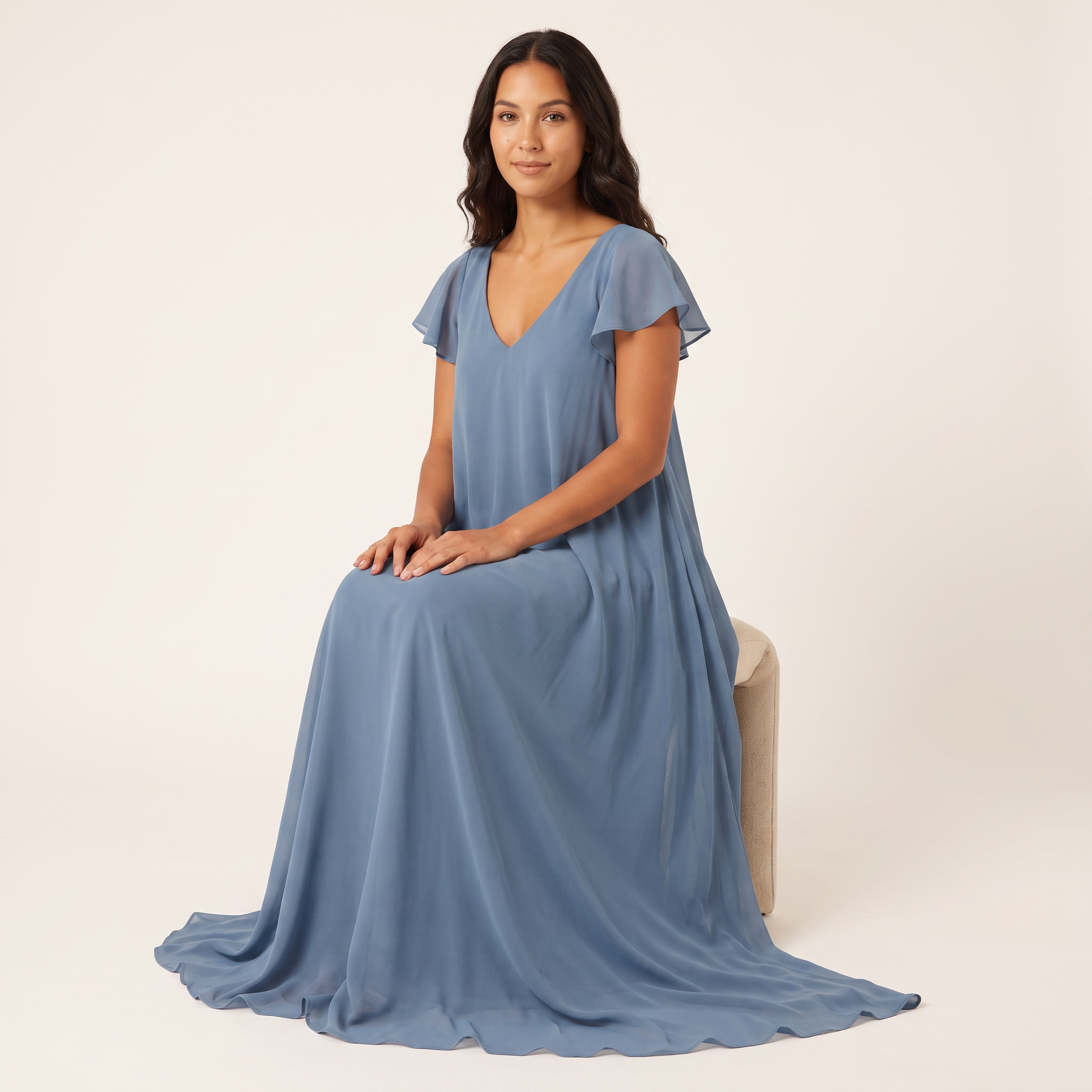 Model seated wearing dusty blue chiffon flutter-sleeve maxi dress