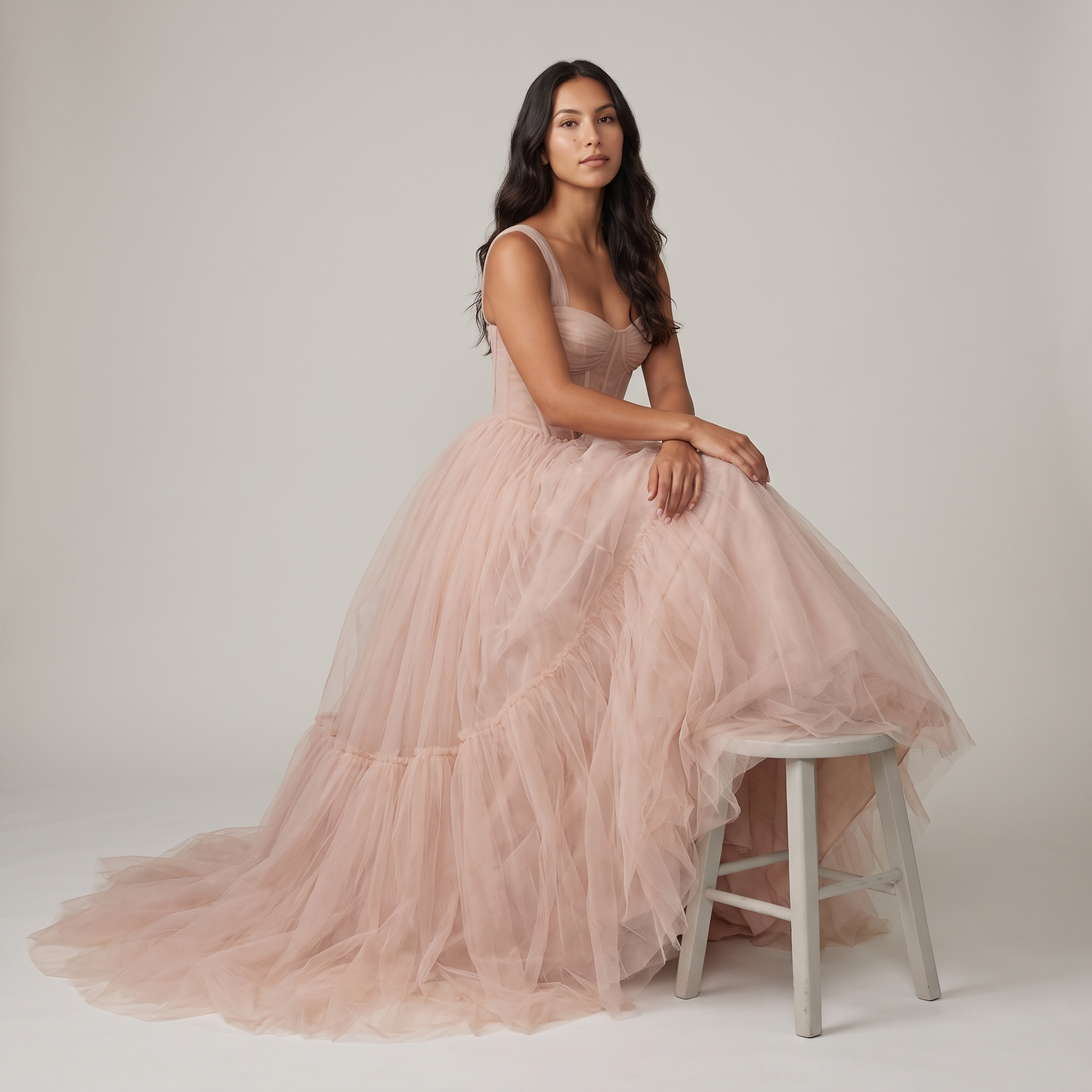 Model seated wearing blush tulle corset ball gown